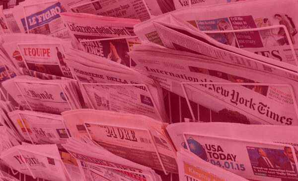 Paper newspapers in metal racks at a newstand.