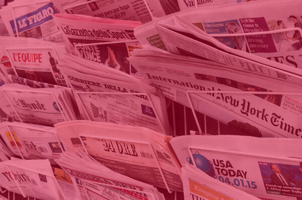 Paper newspapers in metal racks at a newstand.